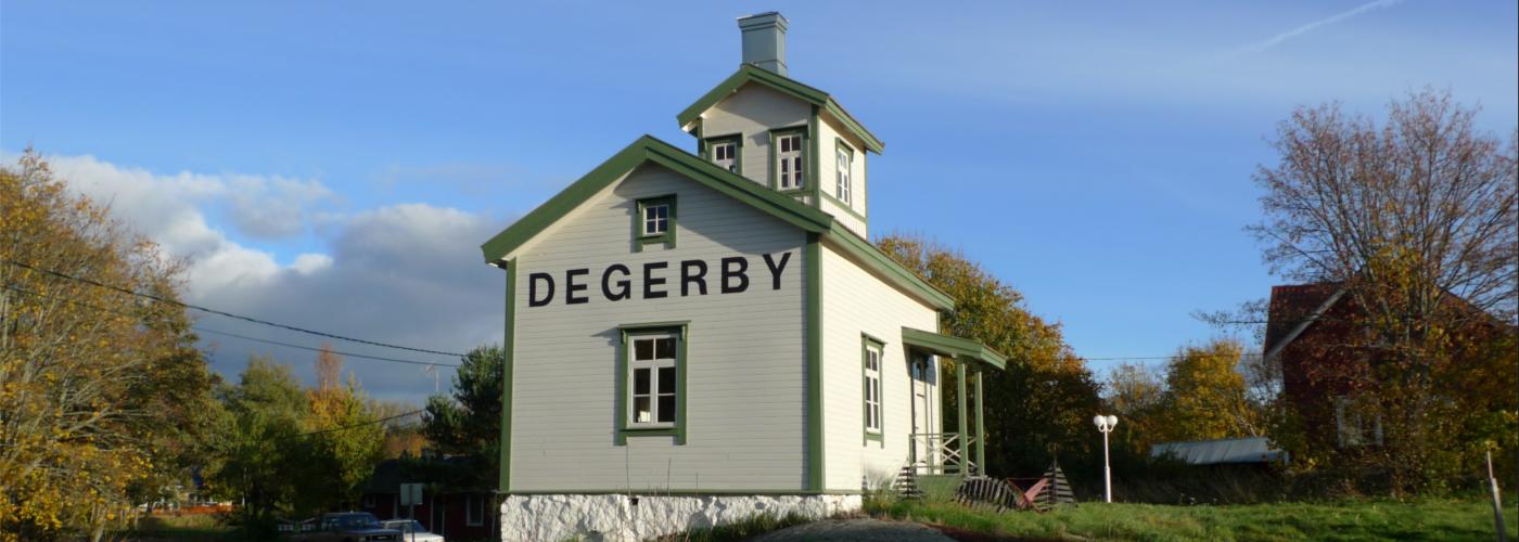 Lotsstugan i Degerby, en liten vit träbyggnad med gröna knutar.