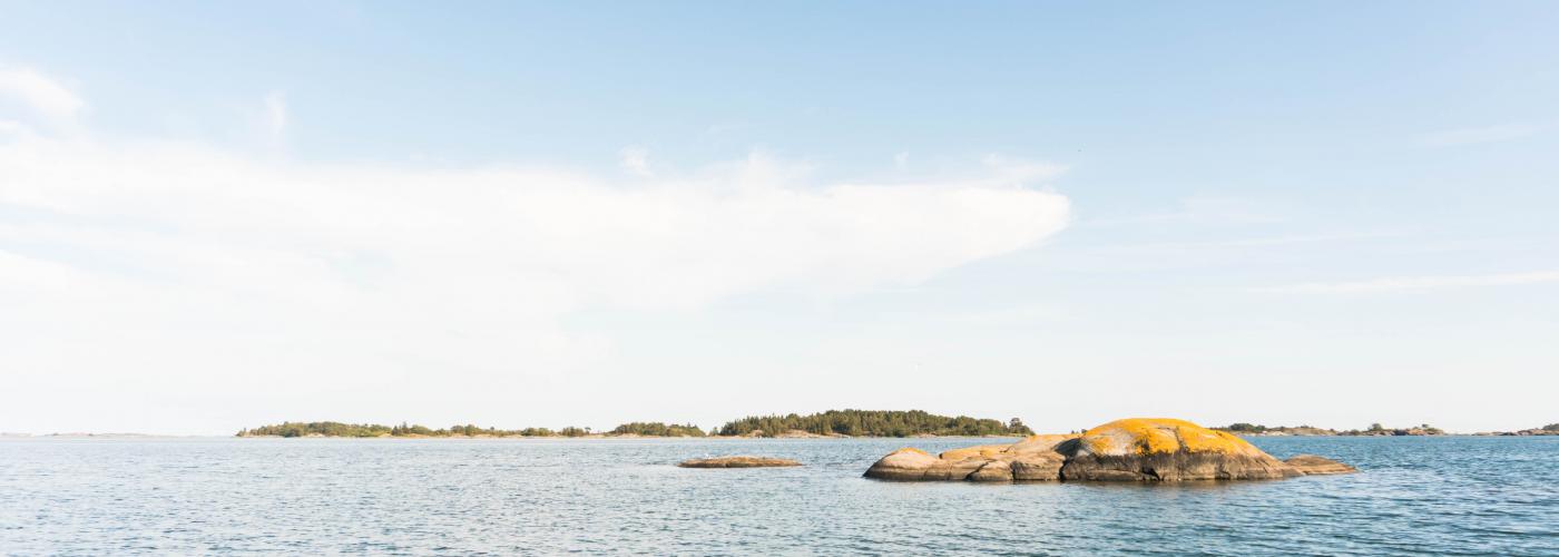 Vy över havet med en ö i bakrunden, en solig sommardag.